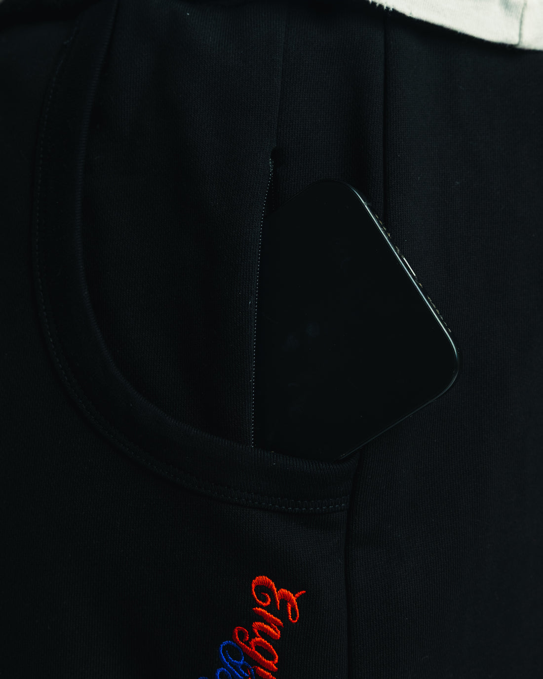 Hidden zip pocket on black Friends Sweats shown holding a phone